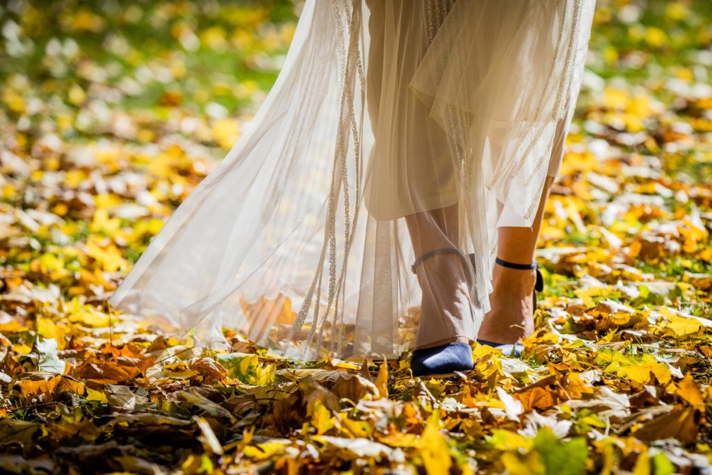 Bride walks through the leaves in heels as the sun shines through her dress