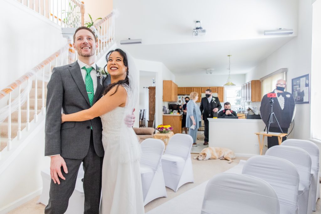 Bride and groom smile at their wedding guests via Zoom