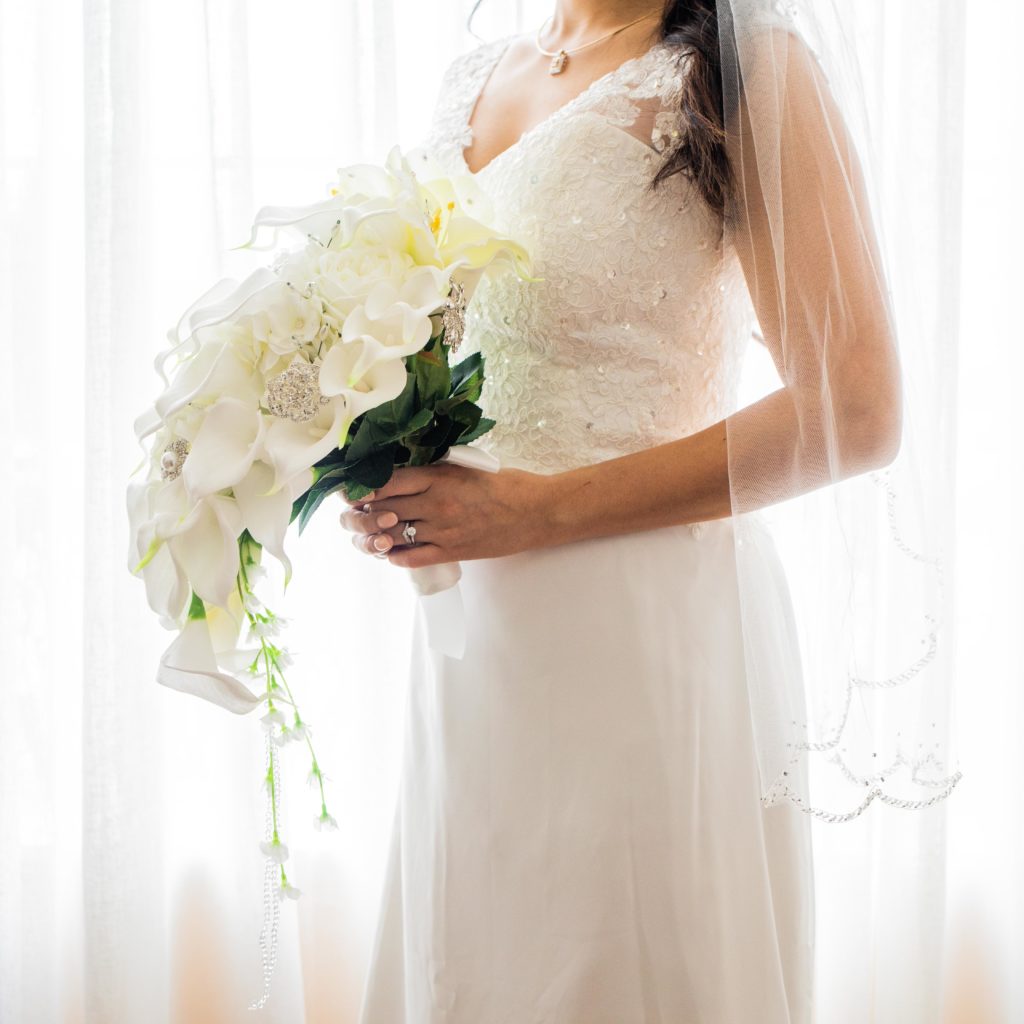 Bride holds fake flowers by the window