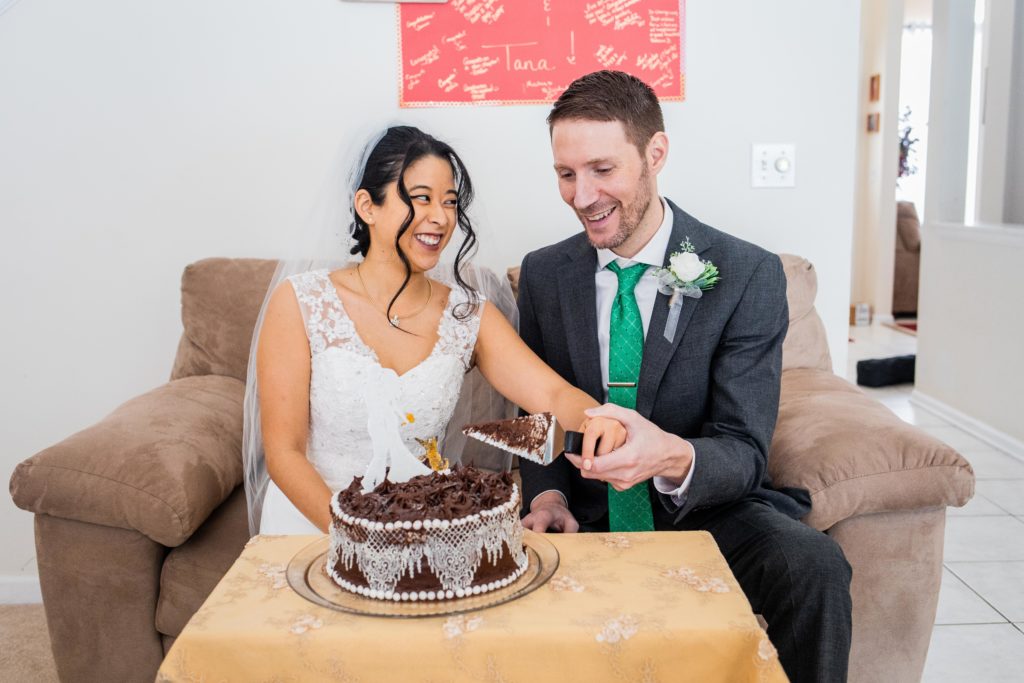 Bride and groom cut the cake on a couch