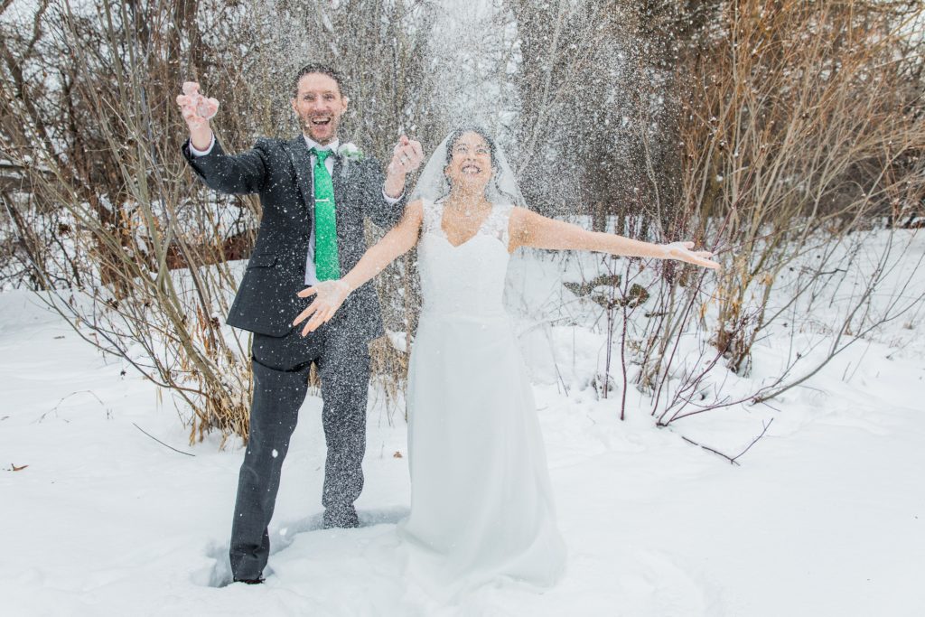 Bride and groom laughing while throwing snow