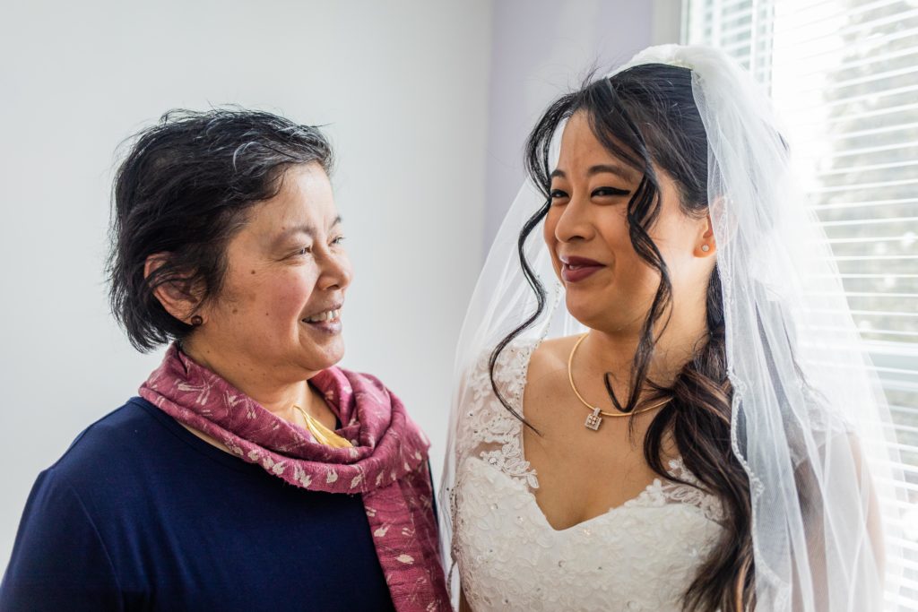 Bride and mom laughing by the window