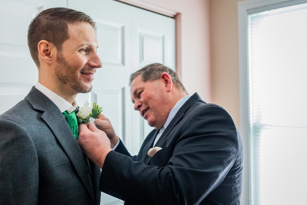 Father putting the boutonniere on the groom 