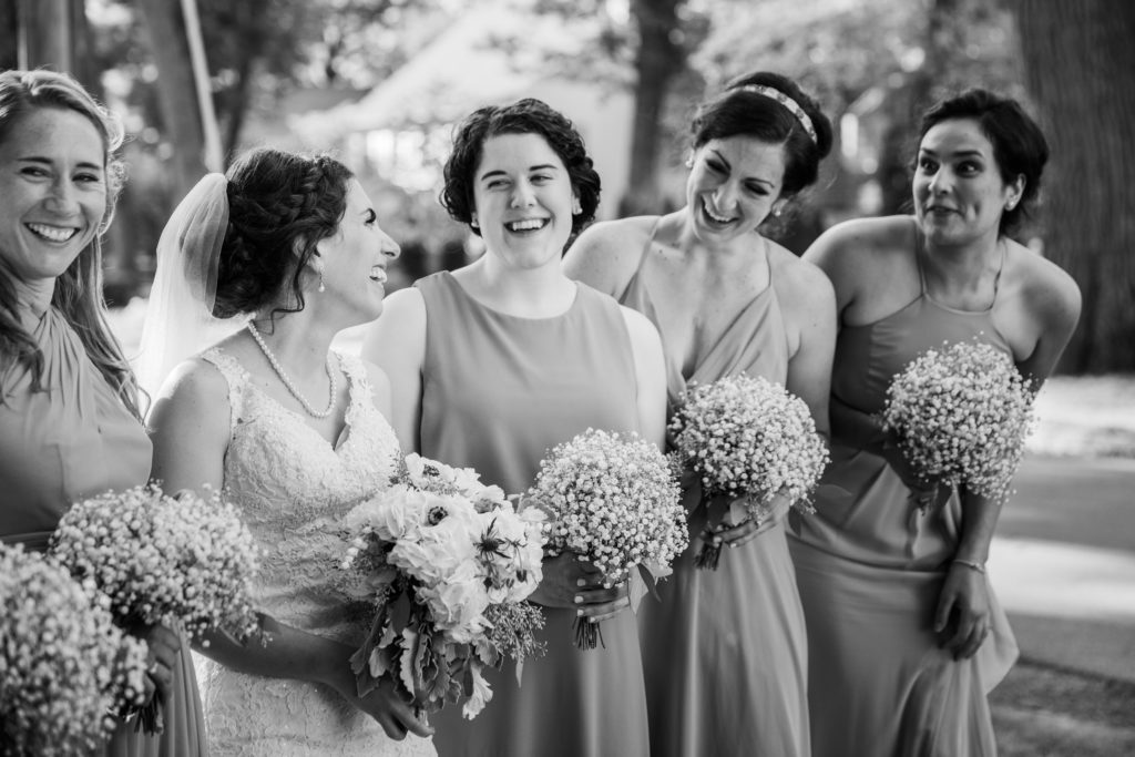 Bride laughs with her bridesmaids in a park in Lake Bluff