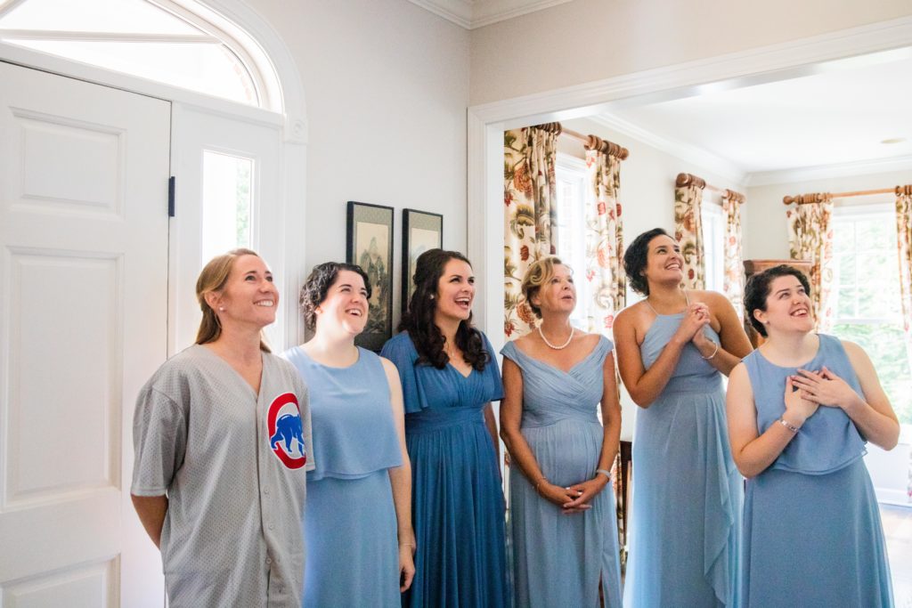 Bridesmaid's in blue dresses watching the bride walk down the stairs