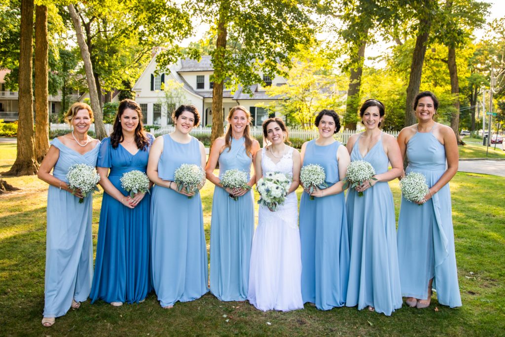 Bride poses with her bridesmaids in a park in Lake Bluff