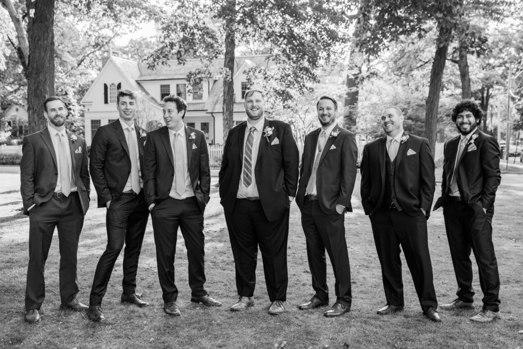 Groom poses with groomsmen in a park in Lake Bluff