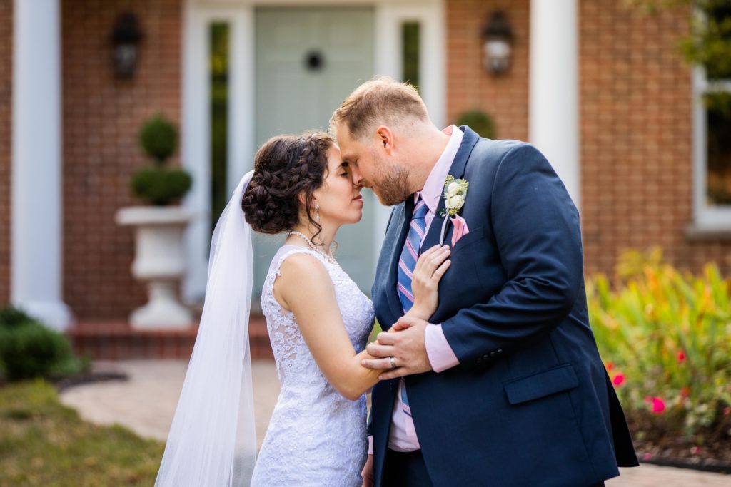 Bride and groom touch foreheads in front of a house