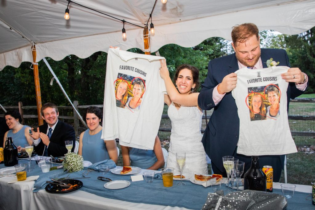 Bride and groom hold up shirts with their cousin's faces on them