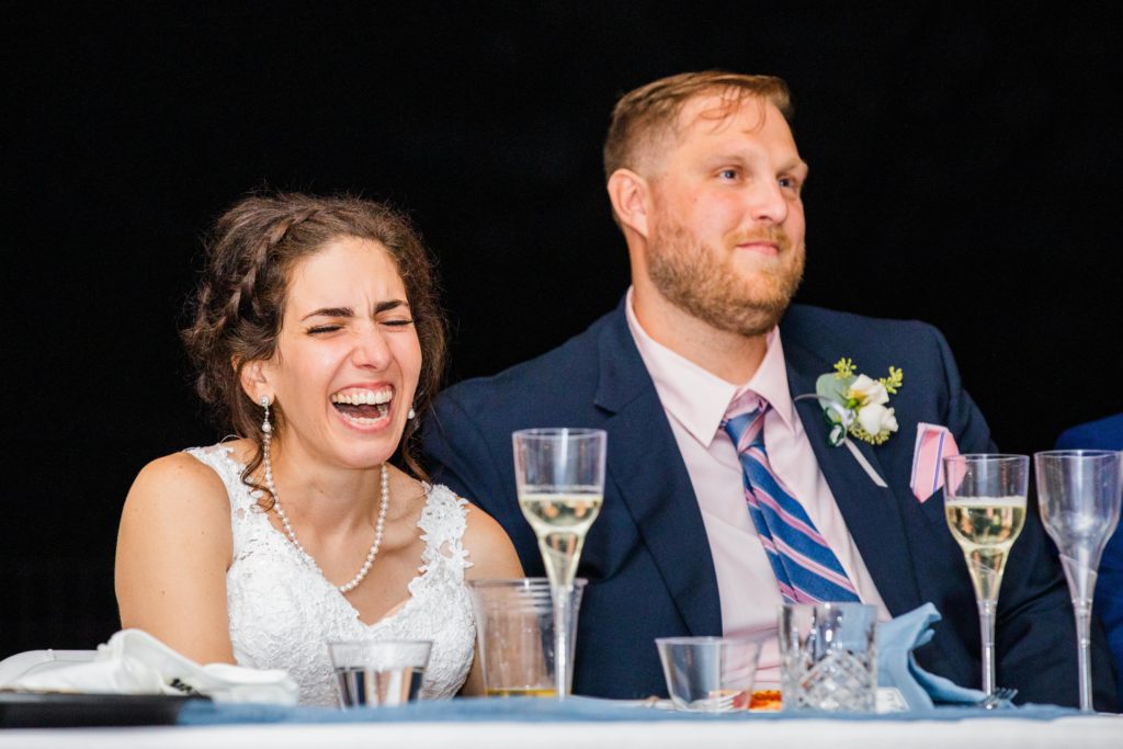 Bride and groom laughing at the dinner table during a speech in Lake Bluff