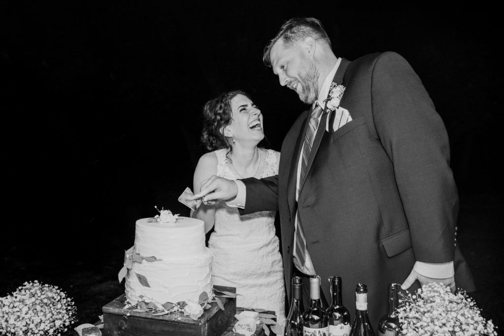 Bride and groom laughing as they cut their cake