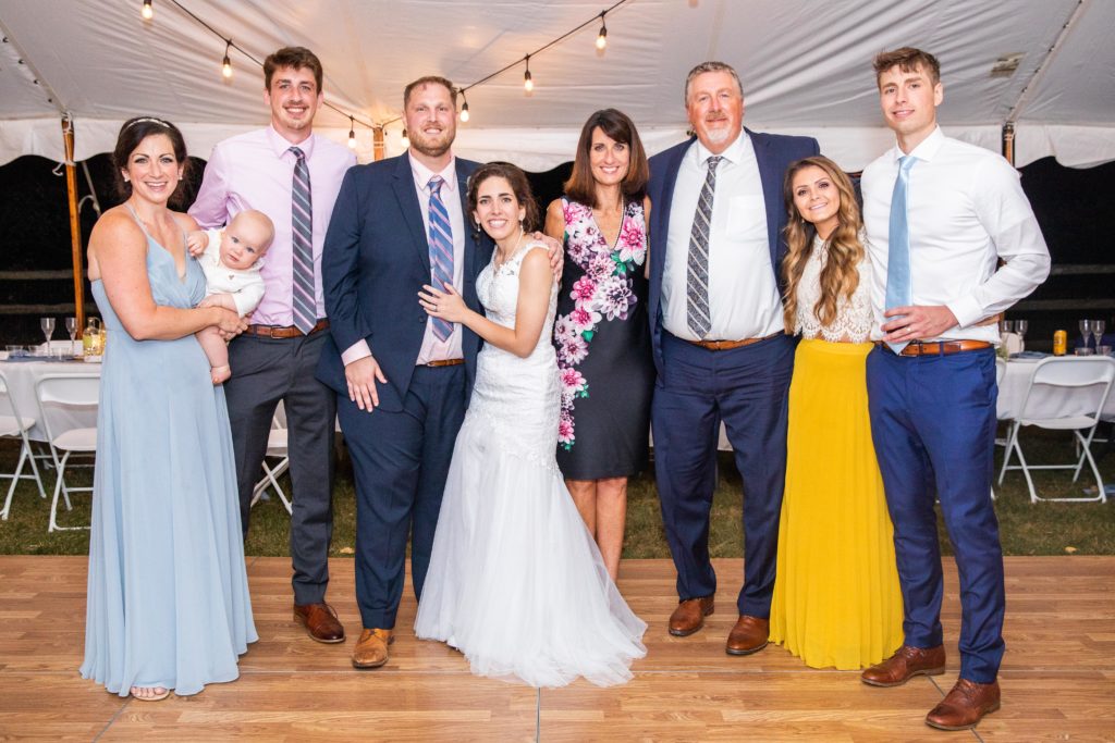 Bride and groom pose with family members for a group photo on the dance floor