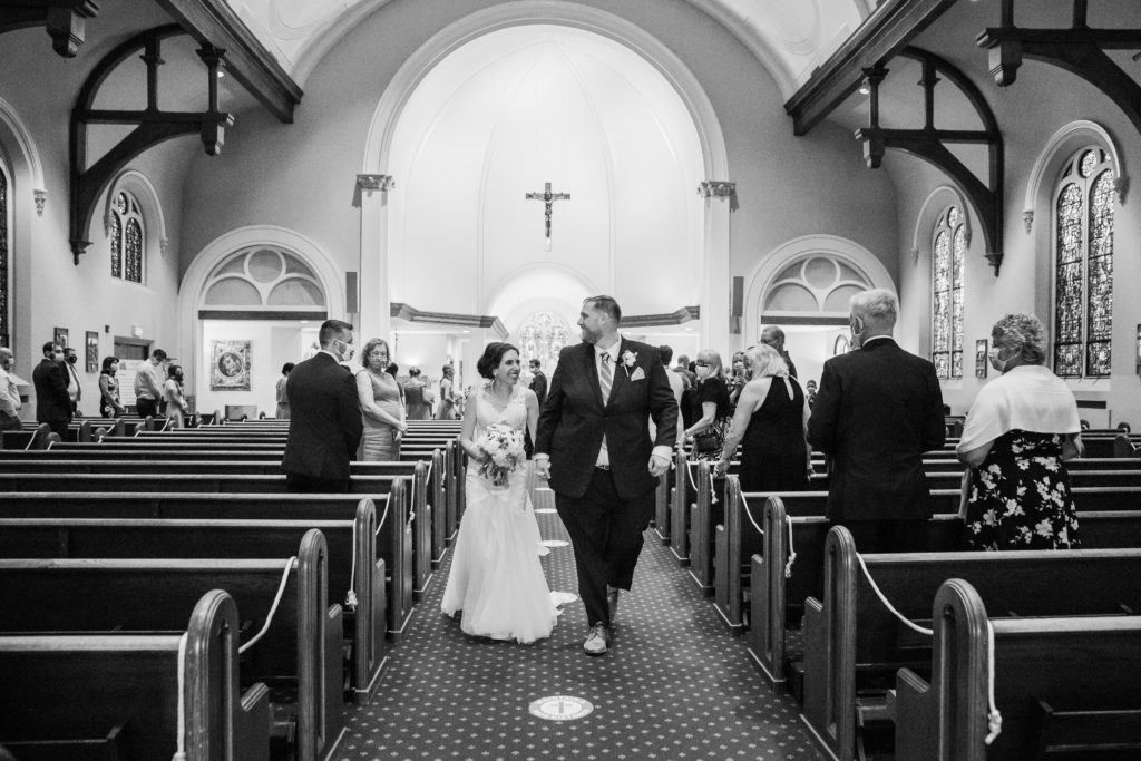 Bride and groom walk hand in hand as they exit the church