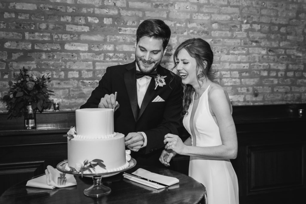 Bride and groom laughing while cutting the cake