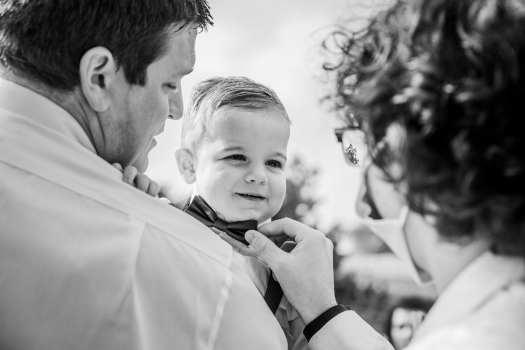 Groom adjusts the bowtie of a small child