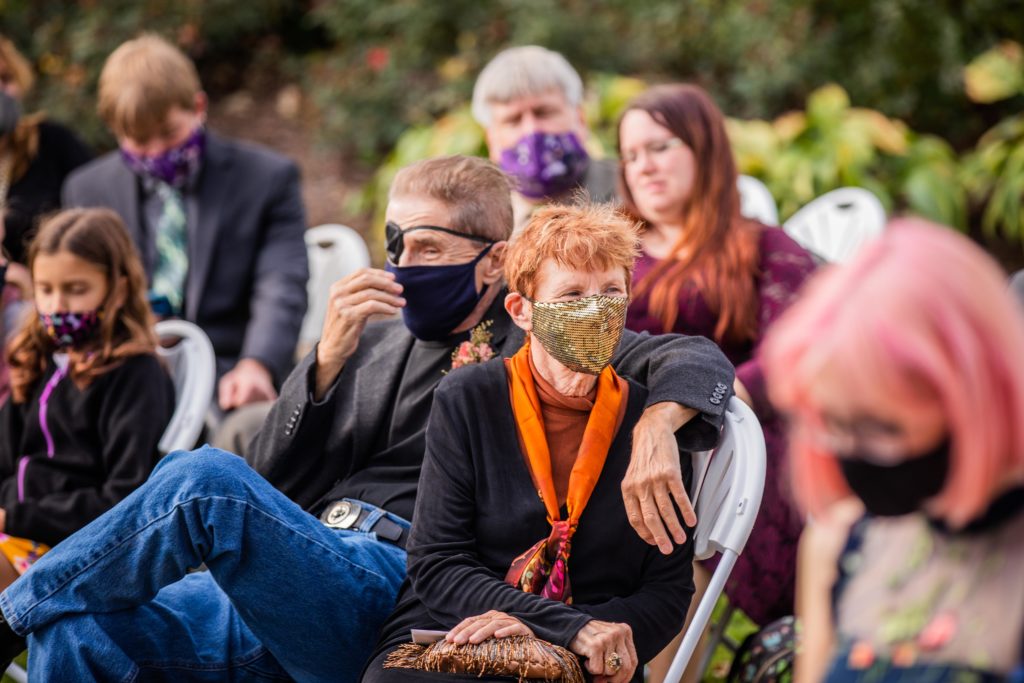 Masked guests sit and wait for the ceremony to begin