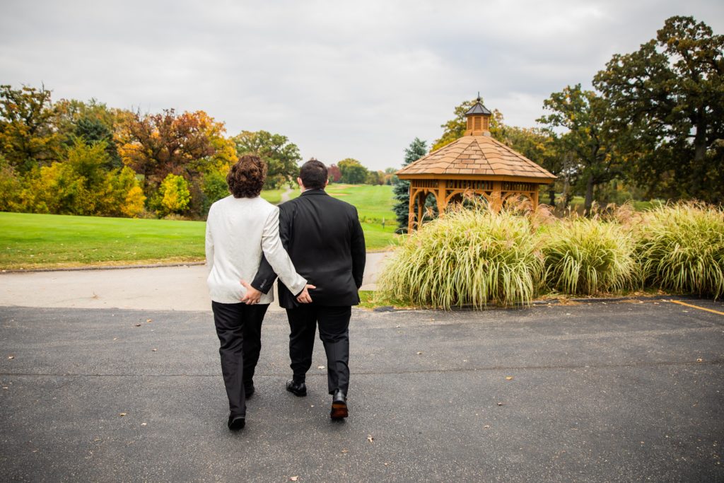 Grooms grab each other's butts as they walk toward a golf course