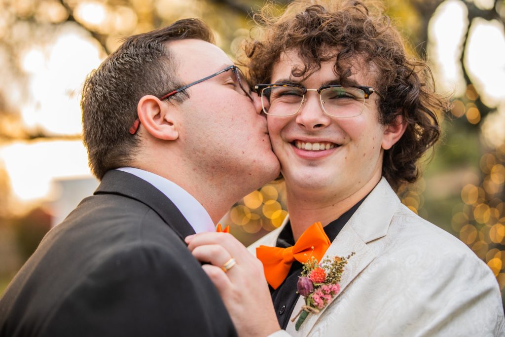 Groom kisses his husband's cheek during their Silver Lake Country Club Wedding