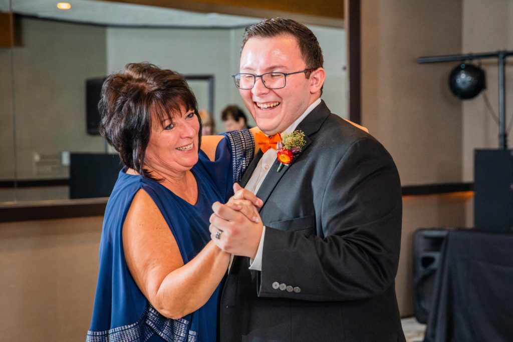 Groom dances with his mother on the dance floor while they smile
