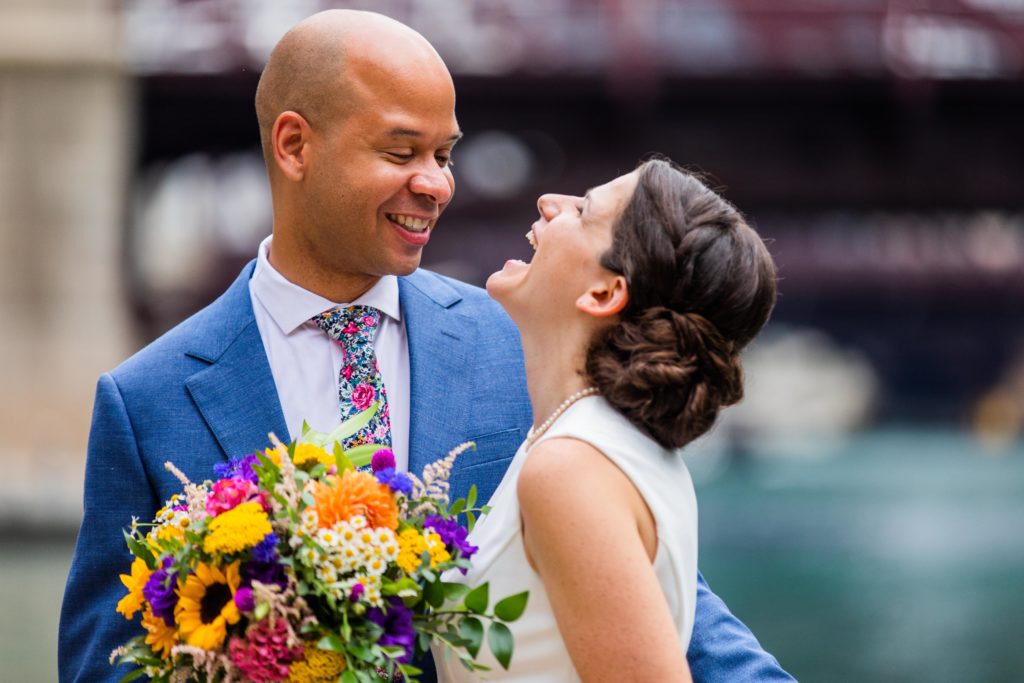 Groom smiles at bride who lets out a big laugh