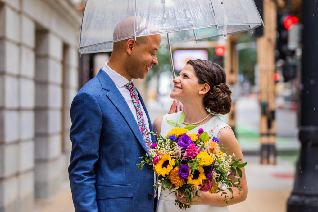 Couple smile at each other while sharing an umbrella