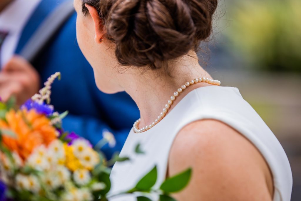 Bride turns her head while wearing a pearl necklace