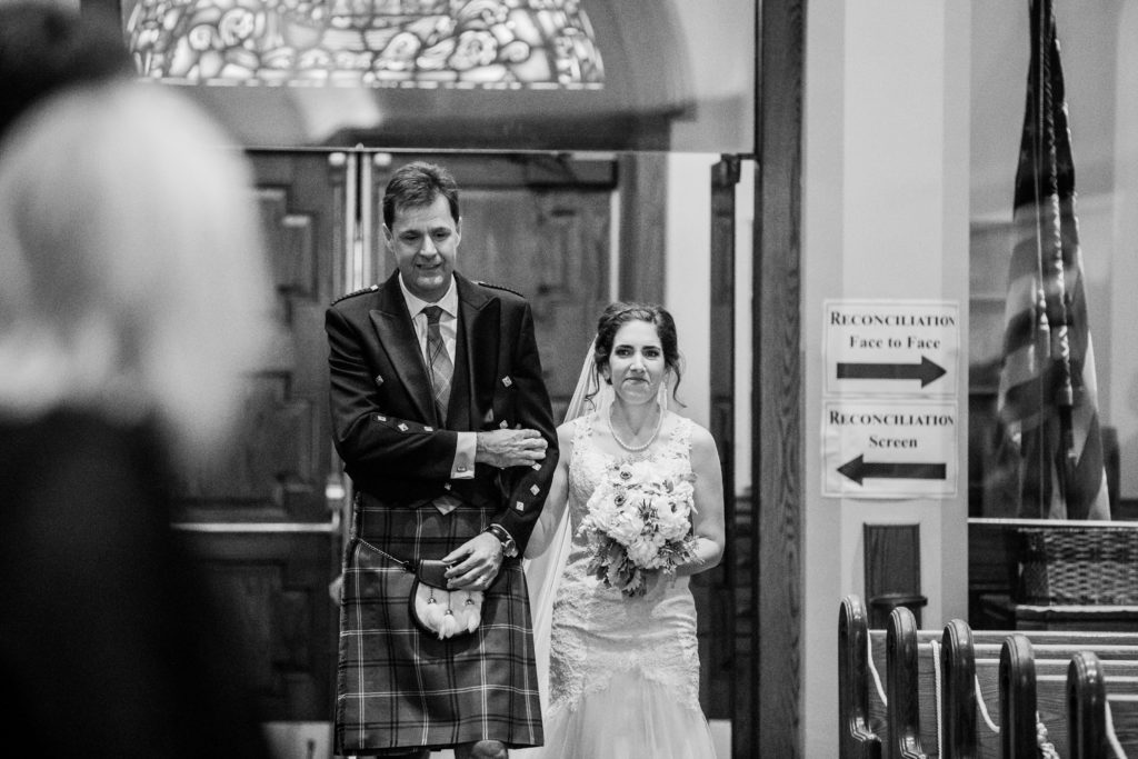 Bride being walked down the aisle by her gather in a kilt