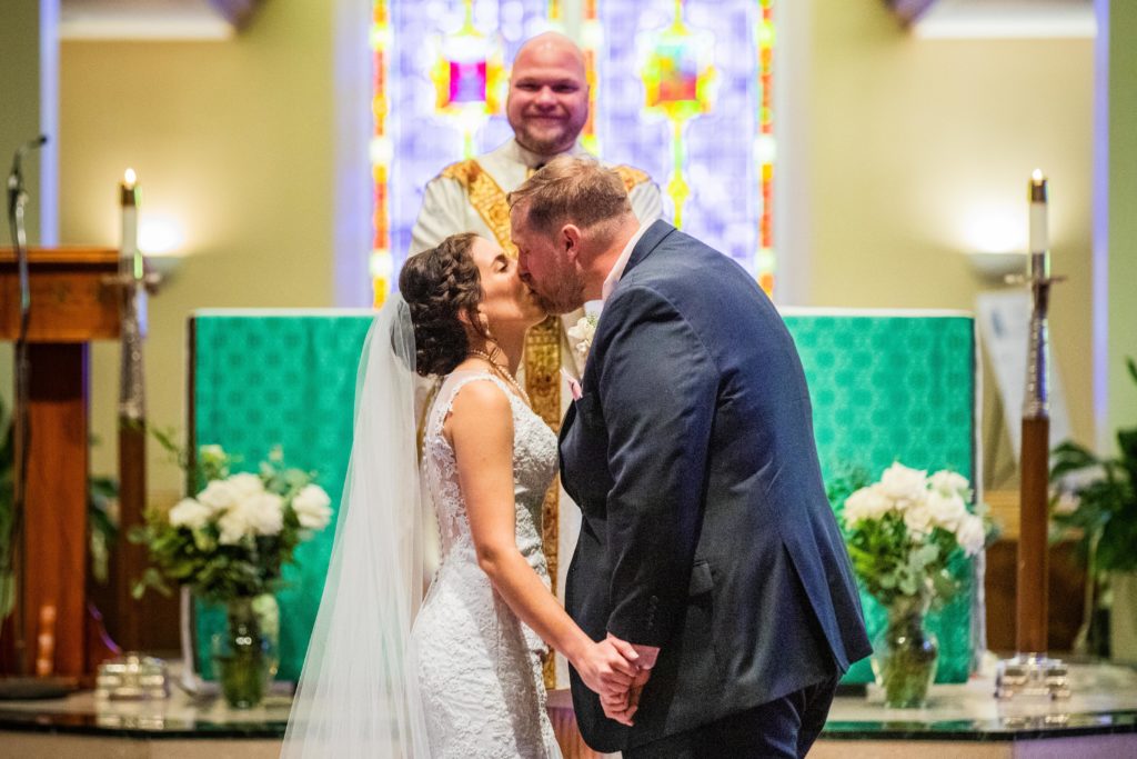 Bride and groom kissing after they say "I do" in a church
