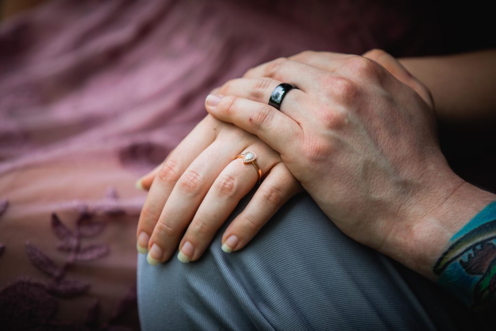 Closeup of couple holding hands with rings