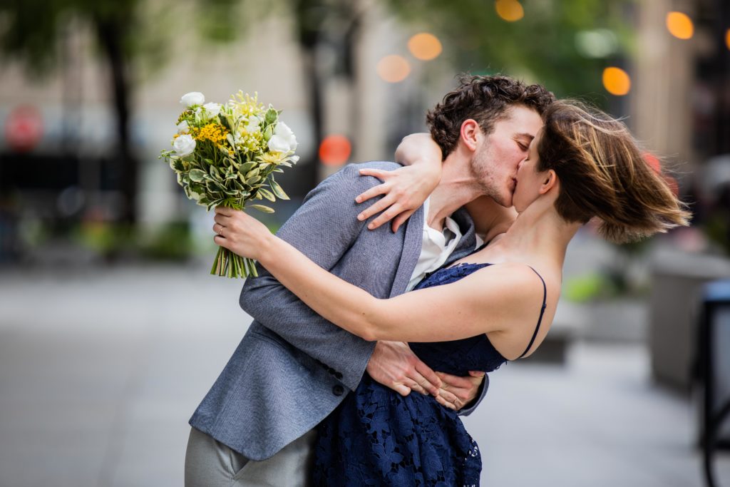 Groom dips and kisses bride in downtown Chicago after their Wedding at City Hall