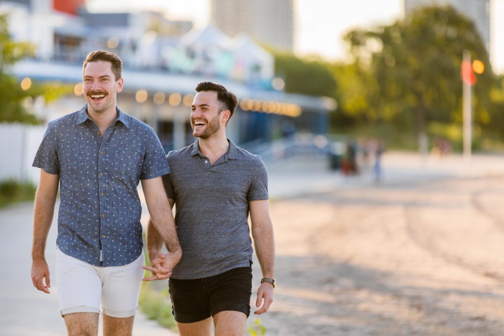 Men holding hands and walking together at North Avenue Beach