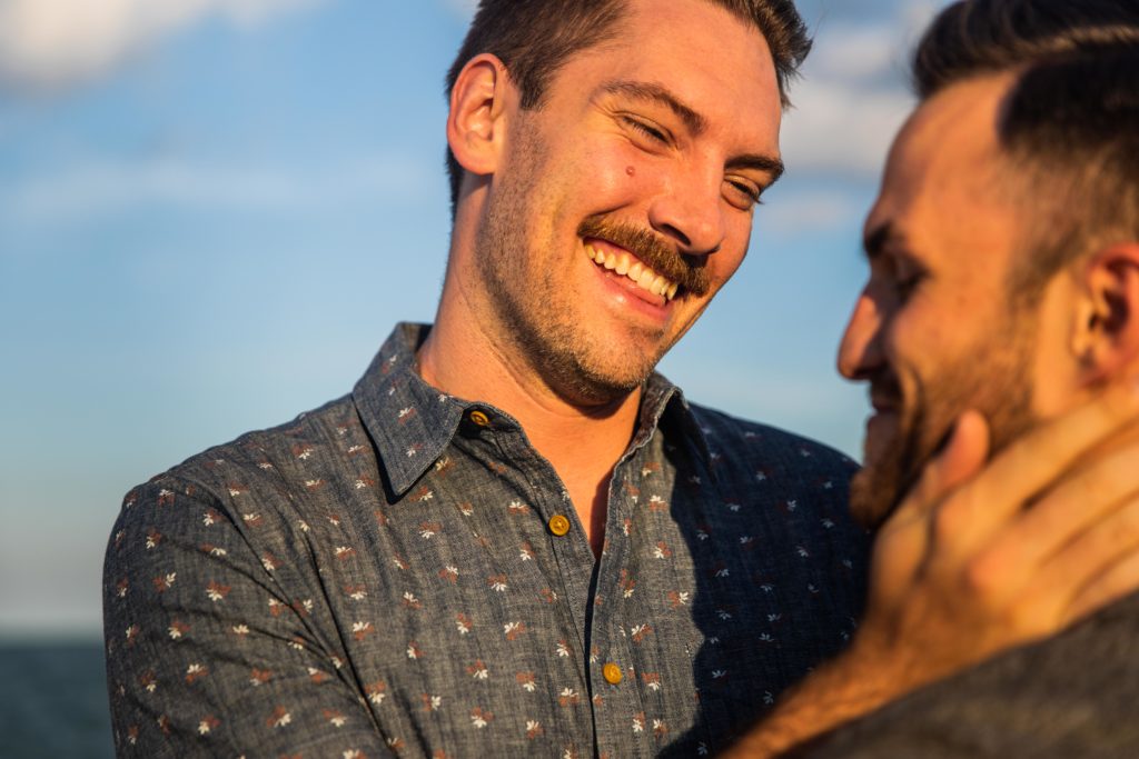 Man holding another man's face while smiling
