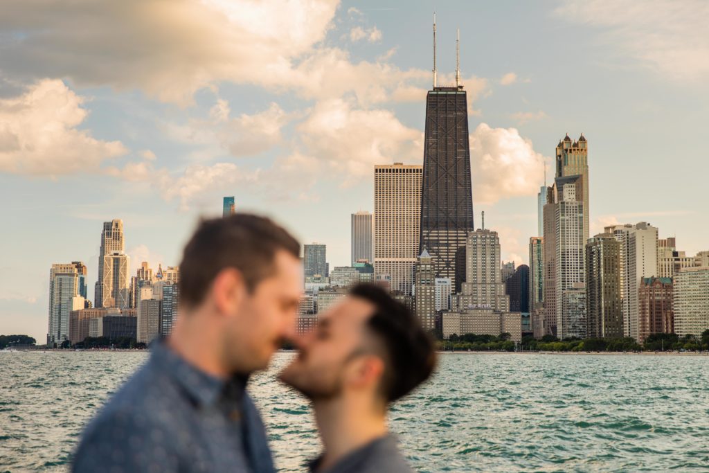 Men touching noses with the Chicago Skyline in the background at North Avenue Beach