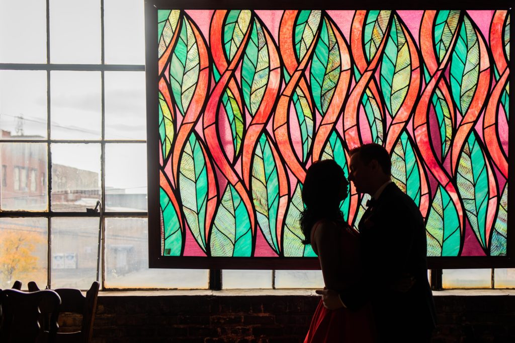 Couple kiss in front of a stained glass window