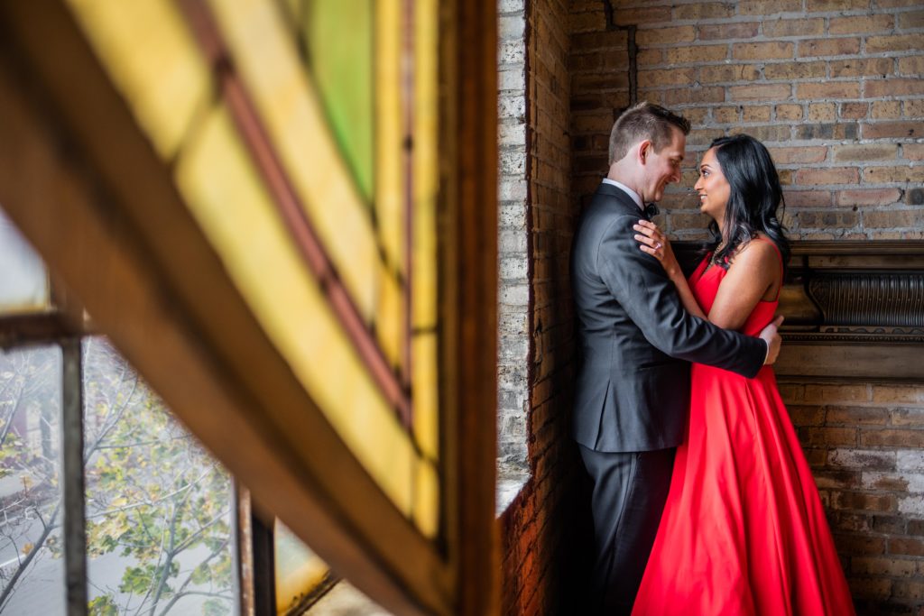 Bride and groom pulling each other close by a window