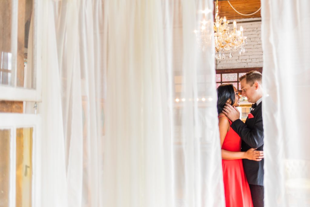 Bride and groom kissing behind a curtain at the Salvage One Wedding Session
