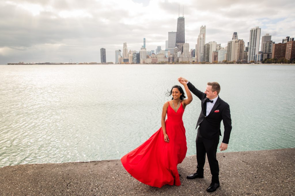 Groom spinning bride in a red dress by the lakefront in Chicago
