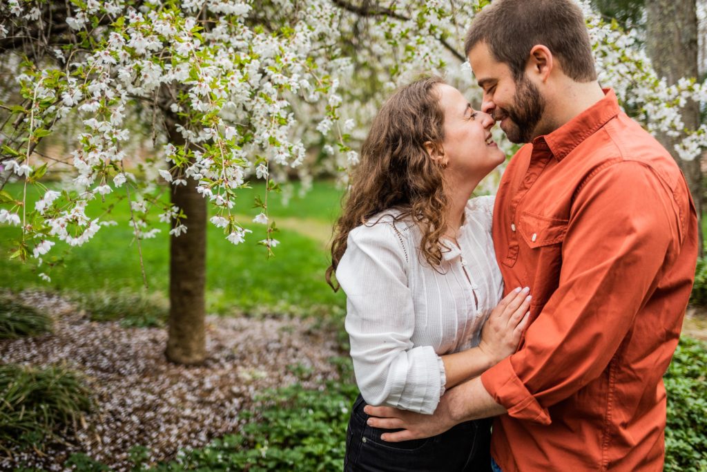 Couple holding each other in front of a blooming tree