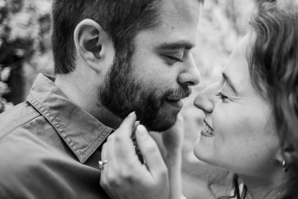 Woman pulls her partner in for a kiss during their engagement session in Bedford