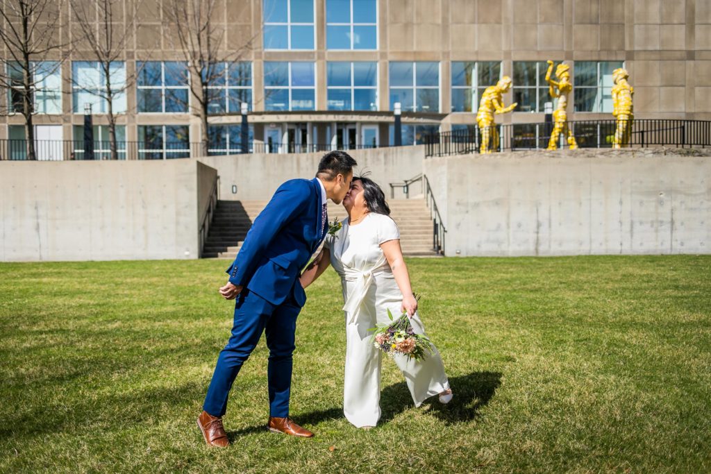 Bride and groom kiss while walking on a lawn in downtown Chicago