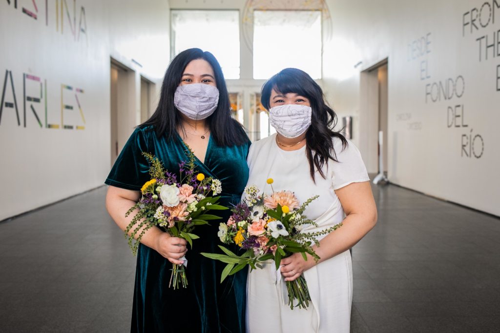 Bride poses with her sister while holding flowers