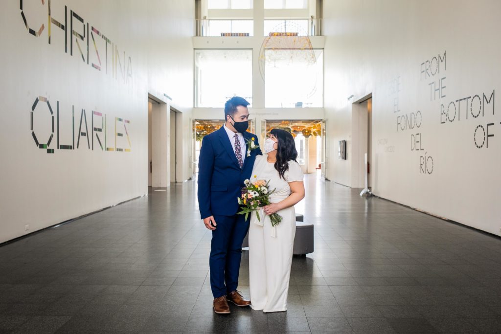 Bride and groom looking at each other in a museum lobby