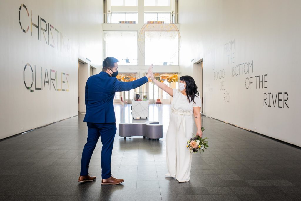 Bride and groom high five in the lobby of the Museum of Contemporary Photography in Chicago