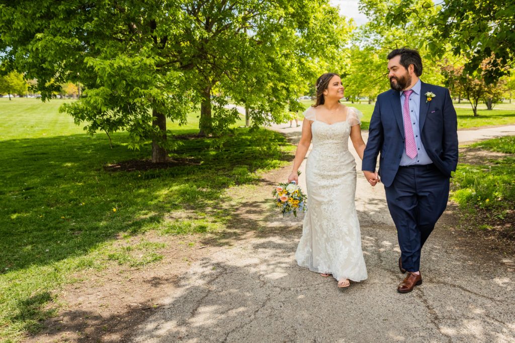 Couple smile and hold hands while walking in Humboldt Park