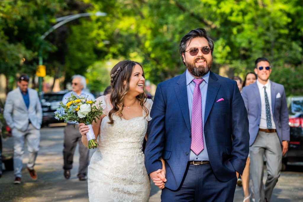 Bride and groom smile in the middle of the street on the way to their Reclaimed Bar and Restaurant Wedding reception