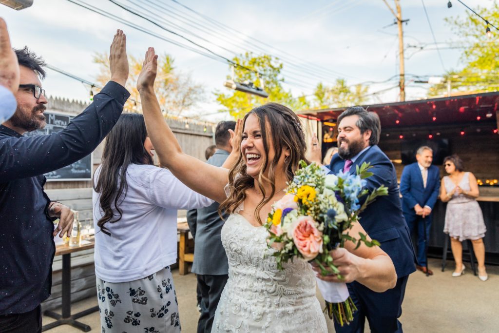 Bride high fives a guest as she runs through a line of people