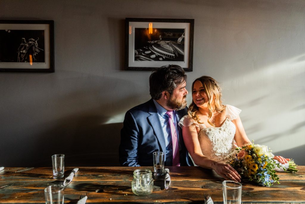 Bride and groom pose in the sunlight inside Reclaimed Bar and Restaurant