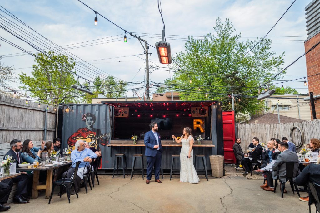 Bride and groom cheers in the back patio of Reclaimed bar and Restaurant
