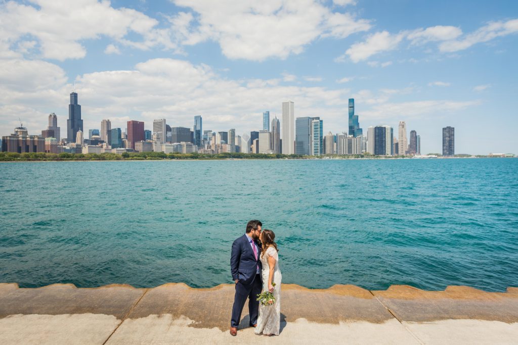 Bride and groom kiss outside of the Adler Planetarium with the Chicago Skyline in the background