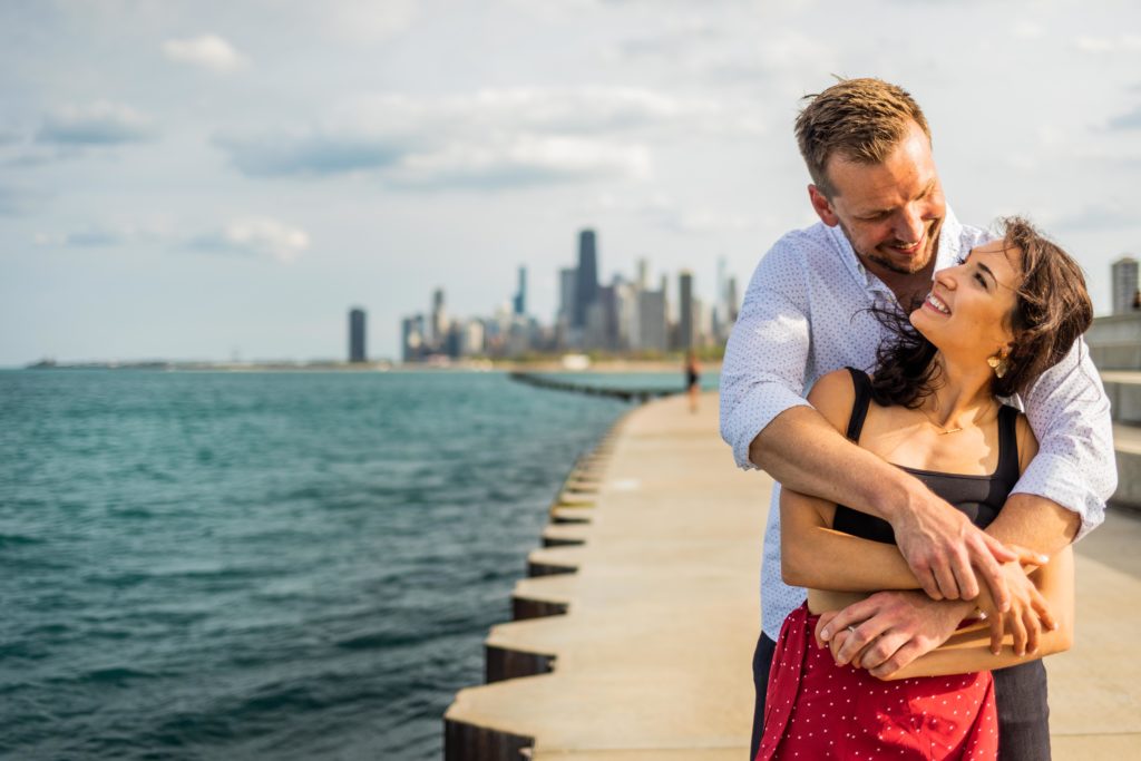 Man holds woman from behind next to the lake during their Lincoln Park proposal